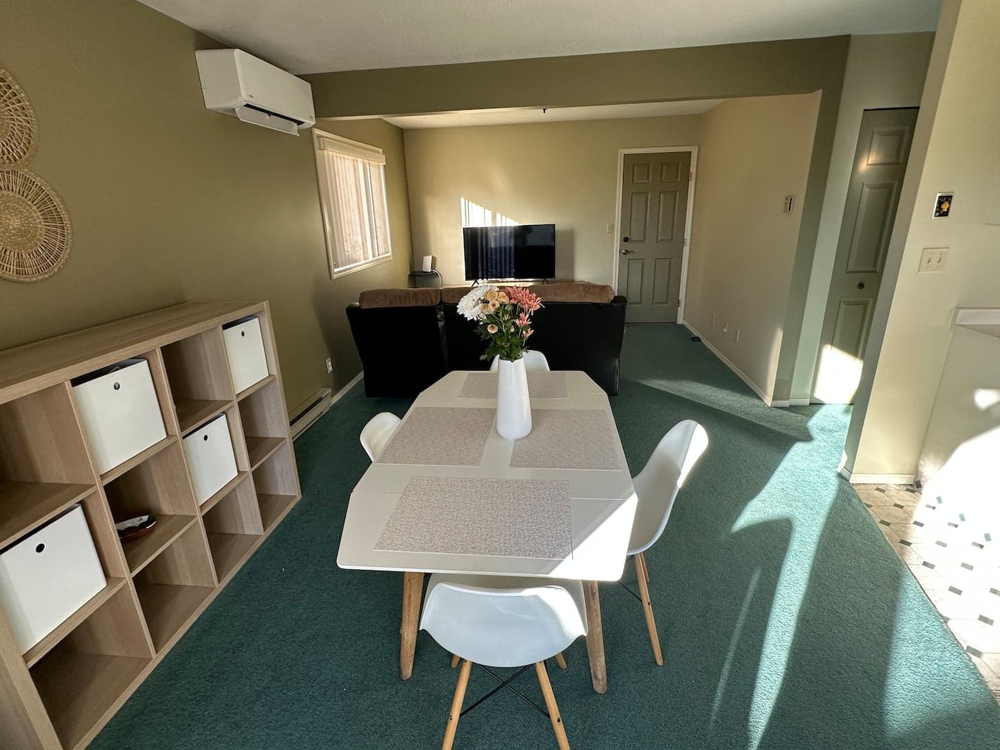 Dining table for four with the living area and TV beyond